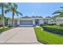 Single-story home with a two-car garage and lush landscaping at 812 Mccallister Ave, Sun City Center, FL 33573