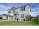 Two-story house with gray siding, gray garage door, and landscaping at 17206 White Mangrove Dr, Wimauma, FL 33598