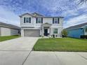Two-story house with gray siding, gray garage door, and landscaping at 17206 White Mangrove Dr, Wimauma, FL 33598
