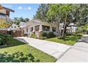 Exterior view of the home with a long driveway, mature trees, and a fenced yard at 2010 W Dekle Ave, Tampa, FL 33606