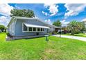 Light blue single-wide home with carport and landscaped lawn at 34334 Timberland Blvd, Wesley Chapel, FL 33543