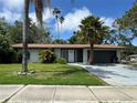 Inviting single-story home with lush lawn, mature palm trees, and an attached garage at 1920 N Highland Ave, Clearwater, FL 33755