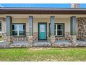 Charming front porch with stone accents, gray columns, and a bright blue door at 8602 State Road 674, Wimauma, FL 33598
