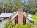 Striking home showcasing a stone chimney, walls of windows, an attached carport, and verdant tropical landscaping at 3520 Leslie West Rd, Dover, FL 33527