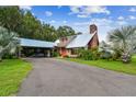 Charming home featuring a metal roof, spacious carport, brick chimney, and lush landscaping, showcasing curb appeal at 3520 Leslie West Rd, Dover, FL 33527
