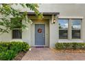 Inviting front entrance with a gray door, decorative wreath, and manicured landscaping at 10066 Corso Milano Dr, Tampa, FL 33625