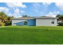 Rear view of a single-story home with gray siding, sliding glass door, and lush green lawn at 16443 Strauss Ave, Port Charlotte, FL 33954
