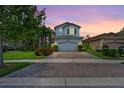 Two-story house with a gray exterior, landscaping, and a two-car garage at dusk at 2847 Tarragona Way, Wesley Chapel, FL 33543