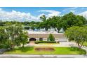 A captivating aerial view shows the home with a lakeside location, mature trees, and well-kept lawn at 3744 E Lake Dr, Land O Lakes, FL 34639