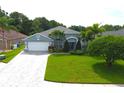 Single-Gathering home with gray exterior, white garage door and lush landscaping at 1842 Ridgelake Ct, Wesley Chapel, FL 33543