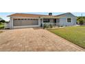 Cute light blue house with a large paved driveway and well-manicured lawn at 609 Fox Hills Dr, Sun City Center, FL 33573