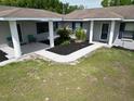 View of the gray home's front porch with fresh black landscaping beds on a grassy lawn at 10223 Us Highway 301, Dade City, FL 33525