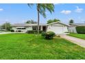 Ranch style home with a large green lawn and driveway at 7015 Flaggler Dr, Port Richey, FL 34668