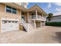 Beautiful beige home with two garages, one under the house and another next to the entrance at 210 Lakeview Dr, Anna Maria, FL 34216