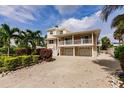 View of a two-story beige house, including the garage and access to the main floor by stairs at 210 Lakeview Dr, Anna Maria, FL 34216