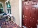 Inviting front entry with a burgundy door and small patio seating at 809 Chipper Dr, Sun City Center, FL 33573