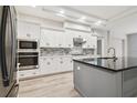 Modern kitchen with gray island, white cabinets, and stainless steel appliances at 19411 Sheltered Hill Dr, Brooksville, FL 34601