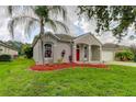 One-story home with red door and lush landscaping at 25954 Risen Star Dr, Wesley Chapel, FL 33544