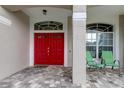 Inviting entryway with a red double door and a covered porch at 25954 Risen Star Dr, Wesley Chapel, FL 33544
