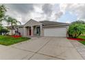 Single-story home with a two-car garage and manicured lawn at 25954 Risen Star Dr, Wesley Chapel, FL 33544