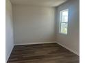 Cozy bedroom featuring wood-look floors, a large window, and neutral paint; a serene retreat at 16029 7Th E Ave, Bradenton, FL 34212