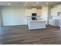 Open-concept kitchen featuring an island, stainless appliances, white cabinets, and wood-look floors at 16029 7Th E Ave, Bradenton, FL 34212