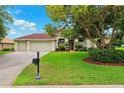 Charming single Gathering home with a well-manicured lawn, mature landscaping, and a two car garage at 13049 Thoroughbred Dr, Dade City, FL 33525