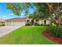 Charming single Gathering home with a well-manicured lawn, mature landscaping, and a two car garage at 13049 Thoroughbred Dr, Dade City, FL 33525