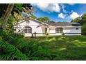 White single story house with a green lawn and mature trees at 3111 Arrowsmith Rd, Wimauma, FL 33598