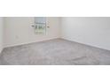 Simple bedroom with grey carpet and a window with blinds at 7864 Broad Pointe Dr, Zephyrhills, FL 33540