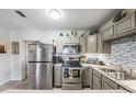 Well-lit kitchen featuring stainless steel appliances, granite counters and tile backsplash at 1611 Stevenson Dr, Clearwater, FL 33755