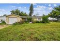 House exterior with a large grassy yard and a single car garage at 1240 Chelsea Ln, Holiday, FL 34691