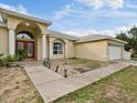 House exterior with a red door, columns, and a walkway leading to the entrance at 13033 Fish Cove Dr, Spring Hill, FL 34609