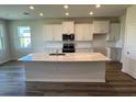 An open kitchen with an island, complete with white cabinets, modern appliances, and countertops at 18142 Beach Ranch Ter, Lakewood Ranch, FL 34211