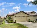 Tan villa with two-car garage, landscaping, and walkway at 227 Mystic Falls Dr, Apollo Beach, FL 33572