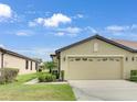 Tan villa with two-car garage, landscaping, and walkway at 227 Mystic Falls Dr, Apollo Beach, FL 33572