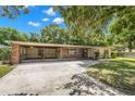 Brick ranch home with carport, mature landscaping, and a spacious yard at 1213 E Frierson Ave, Tampa, FL 33603