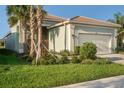 Single-story house with light green exterior, two-car garage, and palm trees at 4838 Sevilla Shores Dr, Wimauma, FL 33598