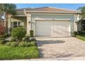 Single-story home with light green exterior, two-car garage, and landscaped yard at 4838 Sevilla Shores Dr, Wimauma, FL 33598