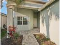 Front entry with light green walls, paver walkway, and tropical landscaping at 4838 Sevilla Shores Dr, Wimauma, FL 33598