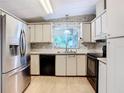 Kitchen with stainless steel appliances, white cabinets, and light-colored flooring at 35801 Verda Dr, Zephyrhills, FL 33541