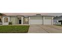 Inviting front exterior with a well-maintained lawn and a three-car garage at 13102 Prestwick Dr, Riverview, FL 33579