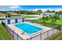 Community pool surrounded by lounge chairs, fenced for safety, and surrounded by lush lawn at 4844 Booth Bay Dr, New Port Richey, FL 34652
