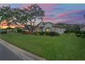 House exterior at sunset with a lush lawn and mature tree at 9315 Fox Hollow Ln, Weeki Wachee, FL 34613