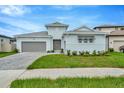 Two-story light blue house with gray double garage and a paved driveway at 10520 Purple Thistle Way, San Antonio, FL 33576