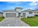 Two-story light blue house with gray double garage and a paved driveway at 10520 Purple Thistle Way, San Antonio, FL 33576