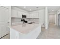 Well-lit kitchen with an expansive island, stainless steel appliances, and modern white cabinets at 20761 Balsam Hill Rd, Land O Lakes, FL 34638