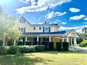 Inviting two-story home featuring a covered porch and well-maintained landscaping at 1109 Belcher Rd, Palm Harbor, FL 34683