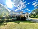 Charming two-story home with a covered entrance, set on a verdant lawn under a sunny sky at 1109 Belcher Rd, Palm Harbor, FL 34683