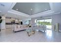 Open-concept living room with modern tile floors, tray ceiling and view of the backyard at 2406 High Tides Way, Wesley Chapel, FL 33543
